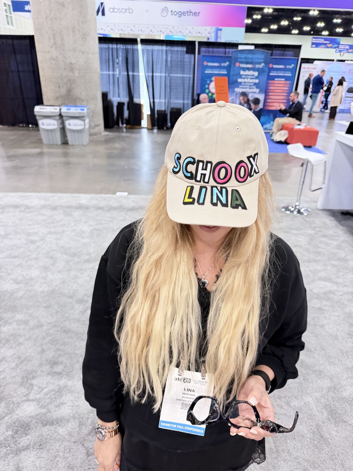 Tan baseball cap personalized with multicolor chenille letters, worn by a smiling guest